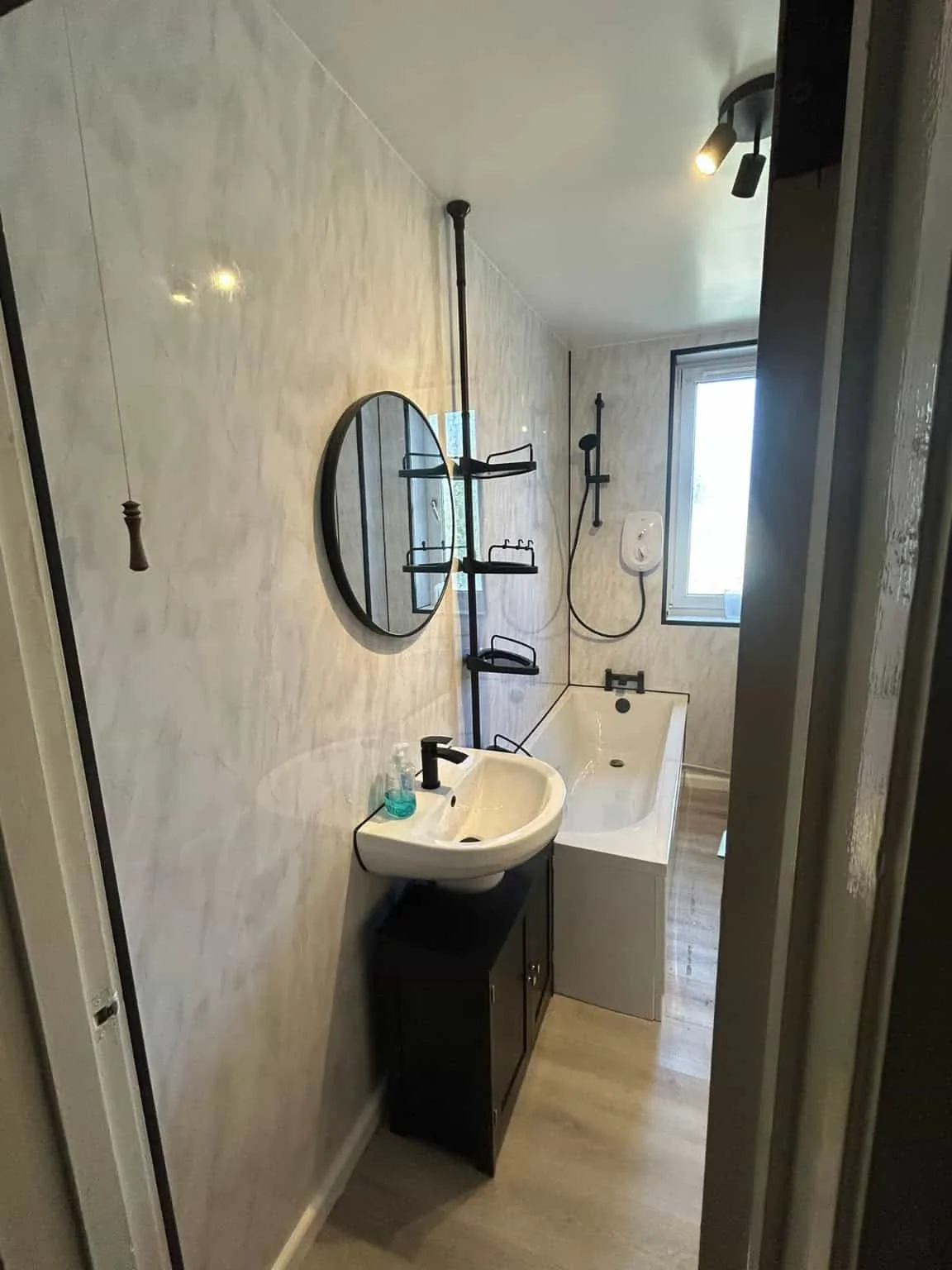 Modern bathroom renovation with marble wall panels and black fixtures